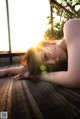 A woman laying on the ground with the sun setting behind her.