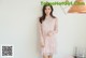 a woman standing in front of a white wall wearing a pink dress