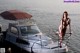 A naked woman standing on a boat in the water.