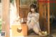 A woman in a white lingerie sitting on a wooden floor.