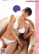 A woman in a white bikini sitting on a chair.